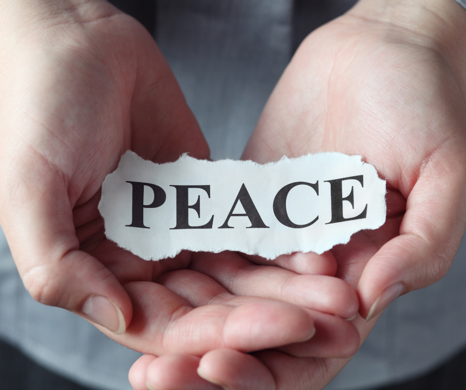 Image of white person's hands holding paper that says Peace