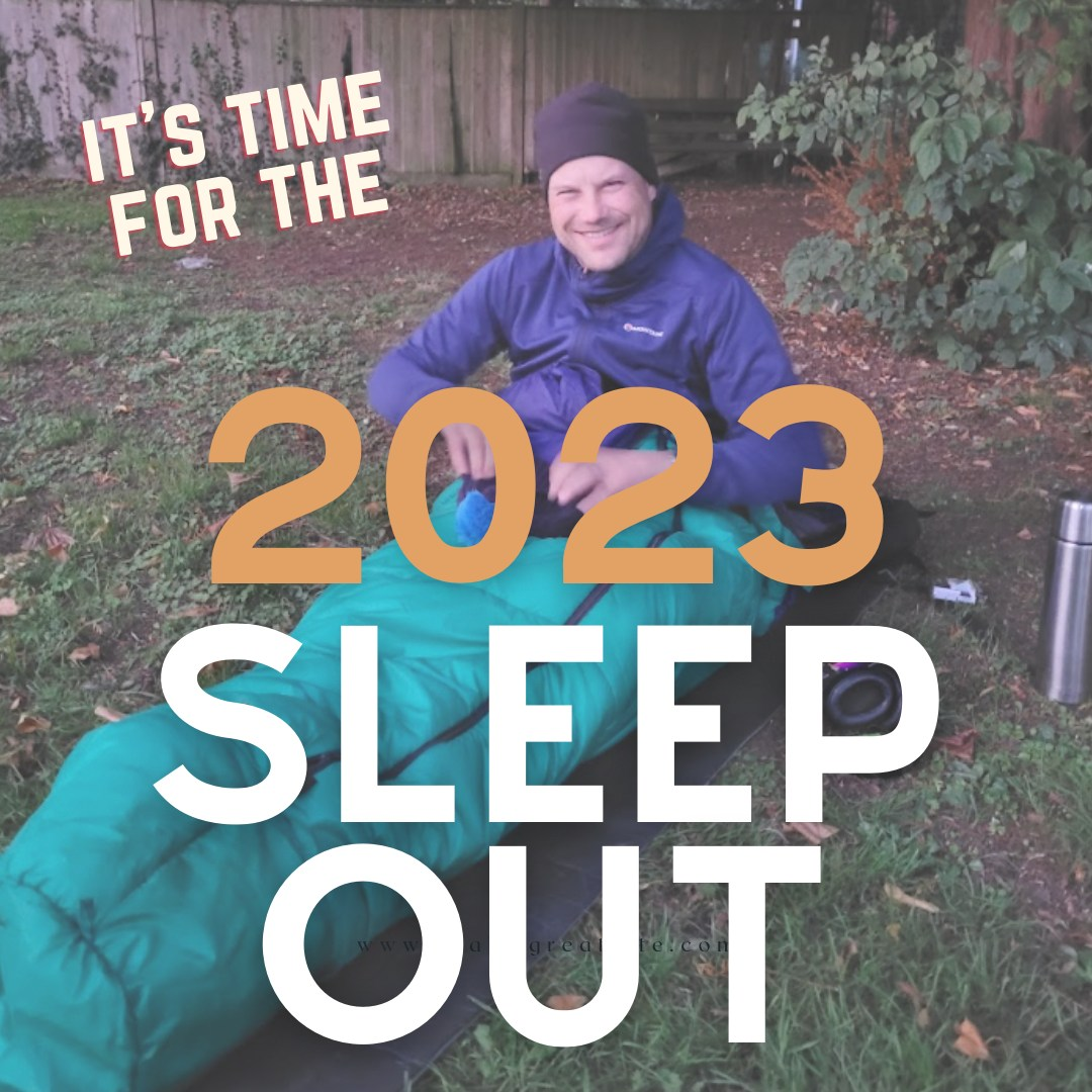 Image of man smiling in sleeping bag on floor. Image overlaid with words It's time for the 2023 Sleep Out