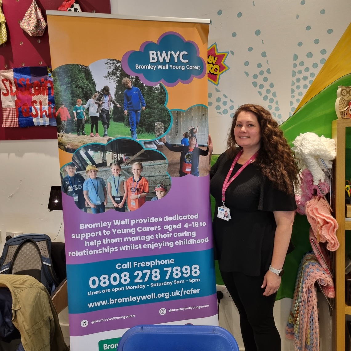 Staff member from Bromley Well Young Carers standing next to sign of organisation
