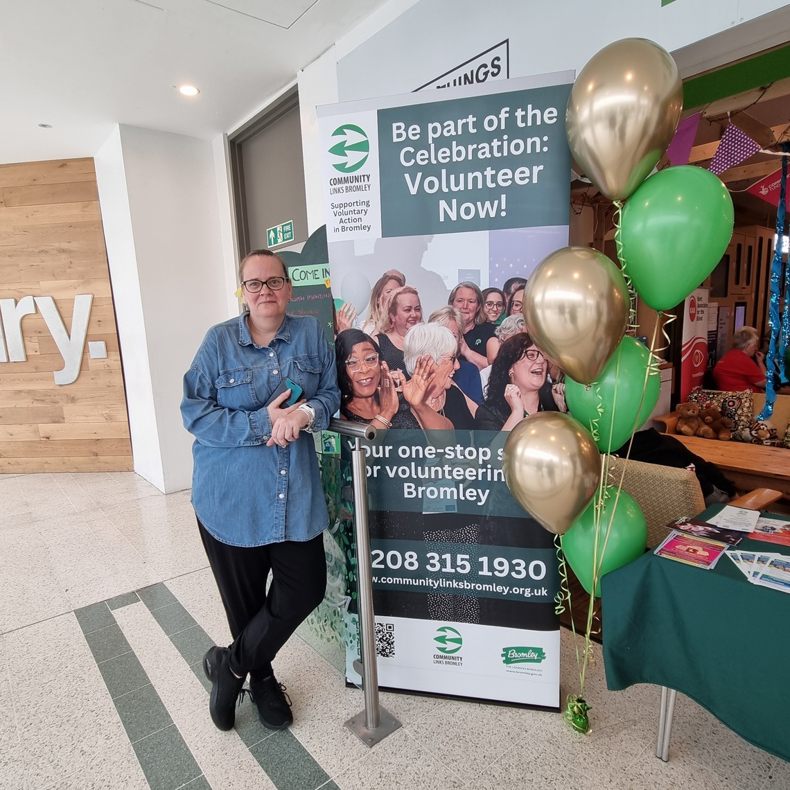 Fay Millen standing next to promotional sign for Community Links Bromley's volunteering services