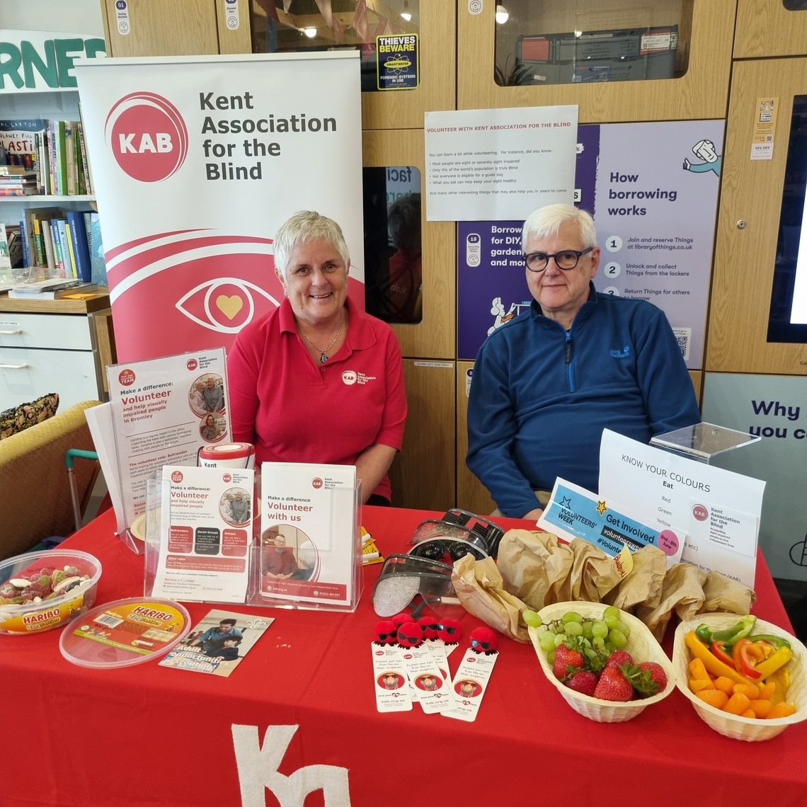 Staff members from Kent Association for the Blind sitting next to sign for charity
