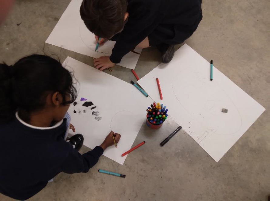 Two children sitting on floor drawing on paper