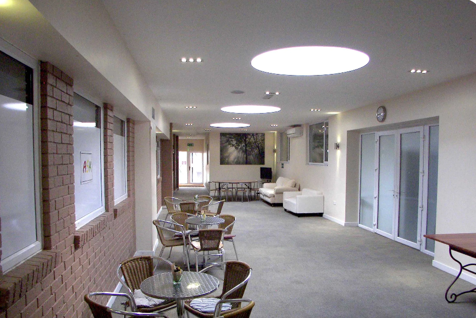 Carpeted atrium with tables and chairs, windows anddoors