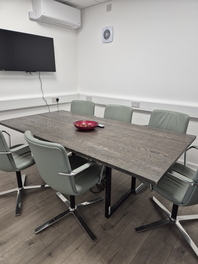 Room with table, chairs and monitor screen on wall