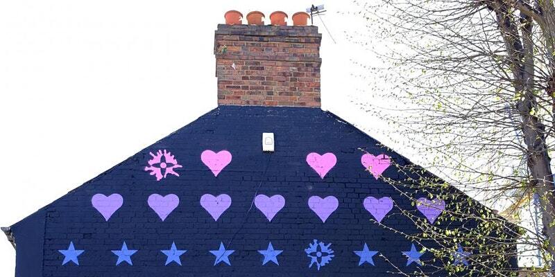 Image of house roof painted blue with colourful lovehearts